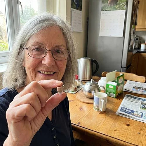 A woman in her seventies holding one Certus device up to the camera